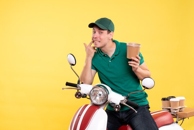 Front view male courier in uniform holding coffee cup on yellow 