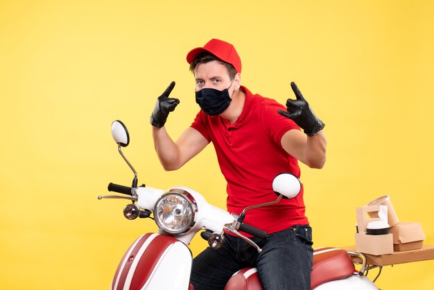 Front view male courier in uniform and mask on yellow 