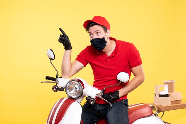 Front view male courier in uniform and mask on yellow 