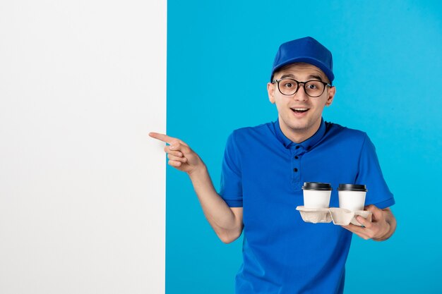 Front view male courier in uniform with coffee cups on blue 