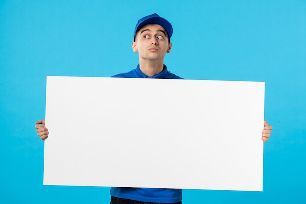 Вид спереди курьера-мужчины в униформе с белым простым столом на синем