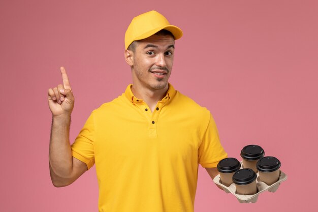 웃 고 분홍색에 배달 커피 컵을 들고 노란색 제복을 입은 전면보기 남성 택배