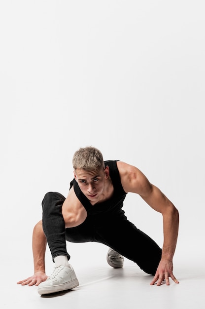 Free photo front view of male dancer in jeans and tank top posing with copy space