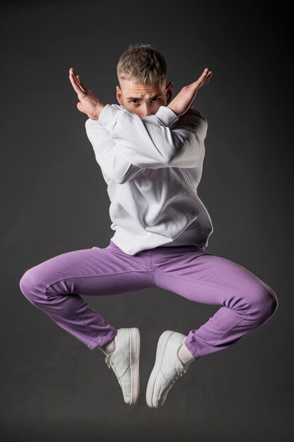 Front view of male dancer in purple jeans posing mid-air