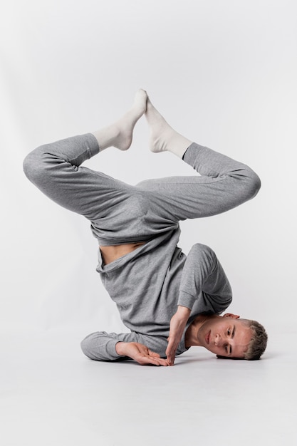 Front view of male dancer in socks and tracksuit posing upside down