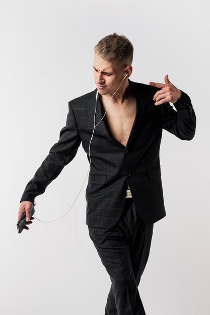 Front view of male dancer in suit posing while listening to music on headphones