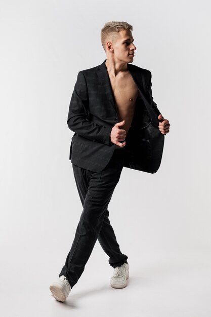 Front view of male dancer in suit and sneakers posing with blazer opened