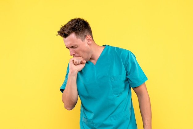 Front view of male doctor biting hand from nerve on yellow wall