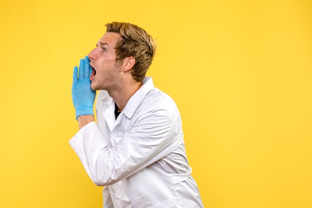 Front view male doctor calling loudly on yellow background covid- human emotion medic