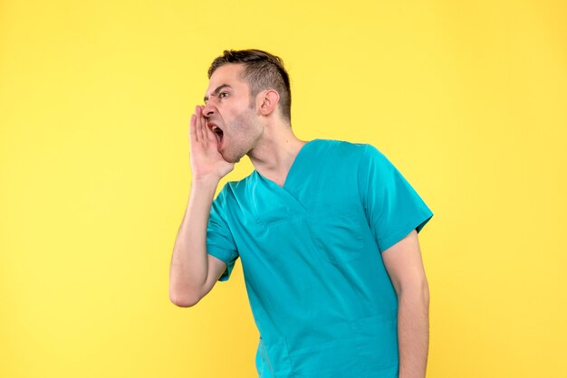 Front view of male doctor calling on yellow wall