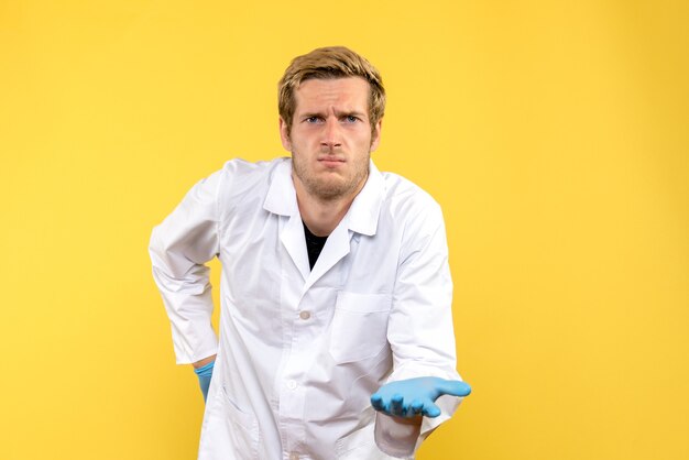 Front view male doctor confused on yellow desk covid- human medic emotion