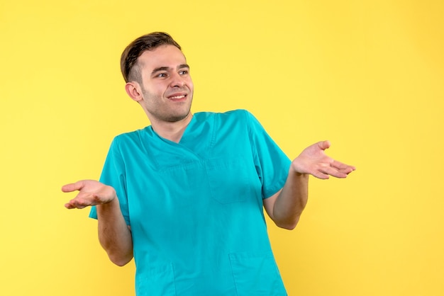 Front view of male doctor confused on yellow wall