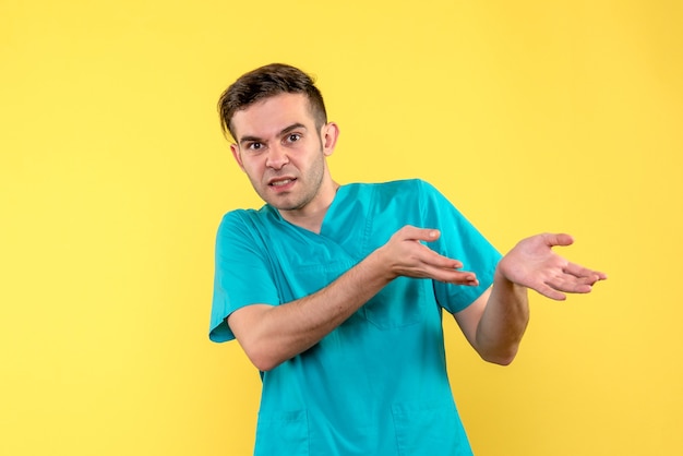 Front view of male doctor confused on yellow wall