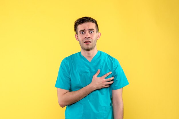 Front view of male doctor confused on yellow wall