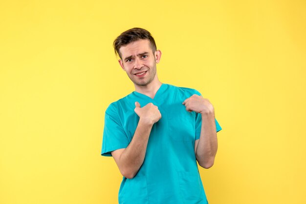 Front view of male doctor confused on yellow wall