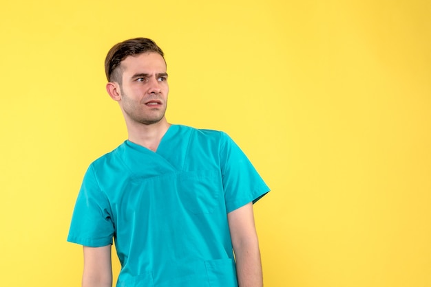 Front view of male doctor confused on yellow wall