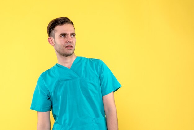 Front view of male doctor confused on yellow wall