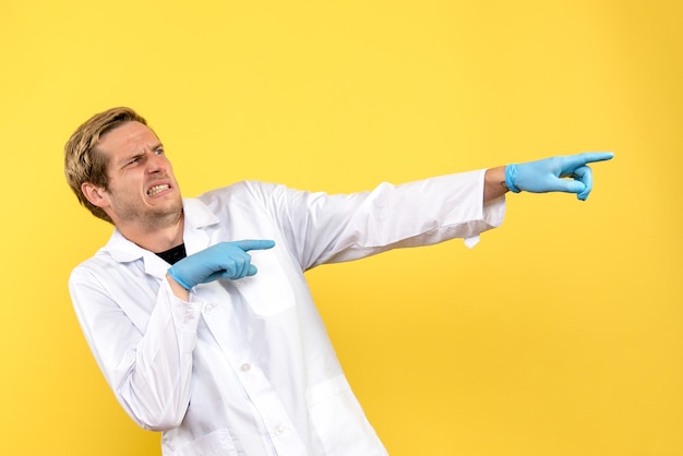 Вид спереди мужчина-врач недоволен на желтом фоне человеческий медик, пандемия covid