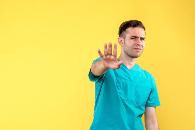 Front view of male doctor displeased on yellow wall