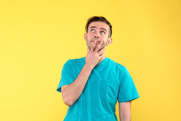 Front view of male doctor dreaming on yellow wall