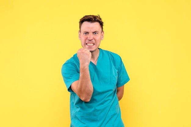 Front view of male doctor emotionally rejoicing on yellow wall