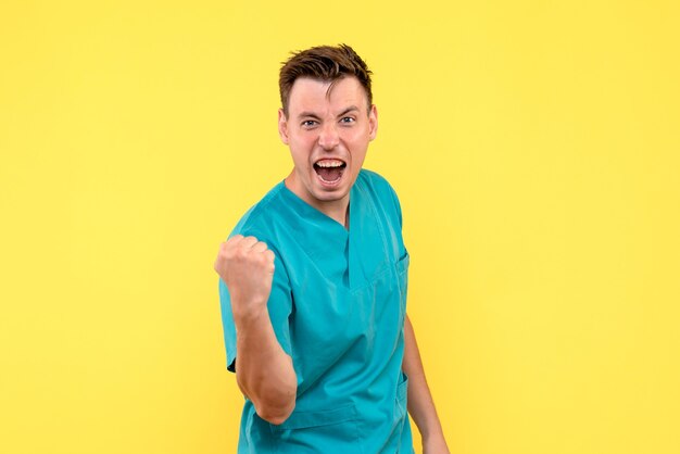 Front view of male doctor emotionally rejoicing on yellow wall