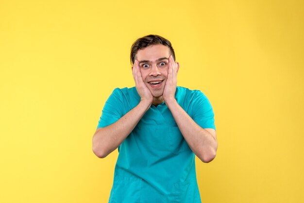 Front view of male doctor excited on yellow wall