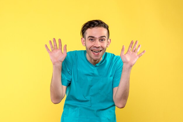 Front view of male doctor excited on yellow wall