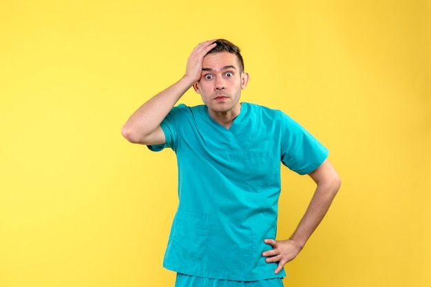 Front view of male doctor excited on yellow wall