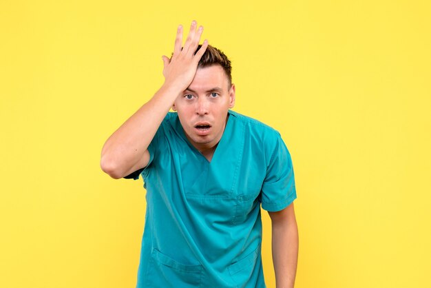 Front view of male doctor feeling nervous on yellow wall