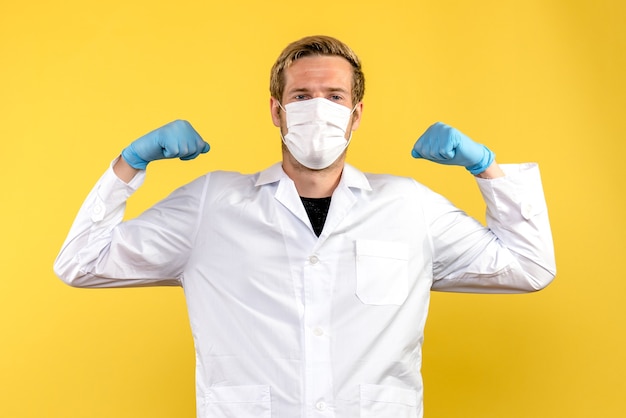 노란색 배경 바이러스 전염병 covid 건강에 마스크에 flexing 전면보기 남성 의사