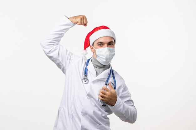 Front view of male doctor flexing on white wall