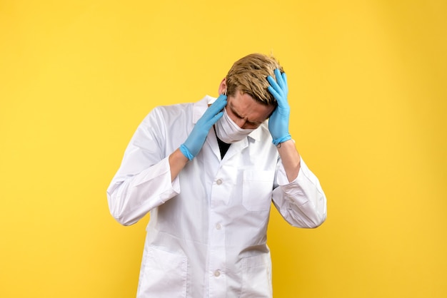 Front view male doctor having headache on yellow background pandemic health covid- virus