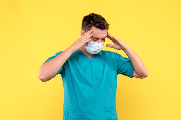 Front view of male doctor having headache on a yellow wall