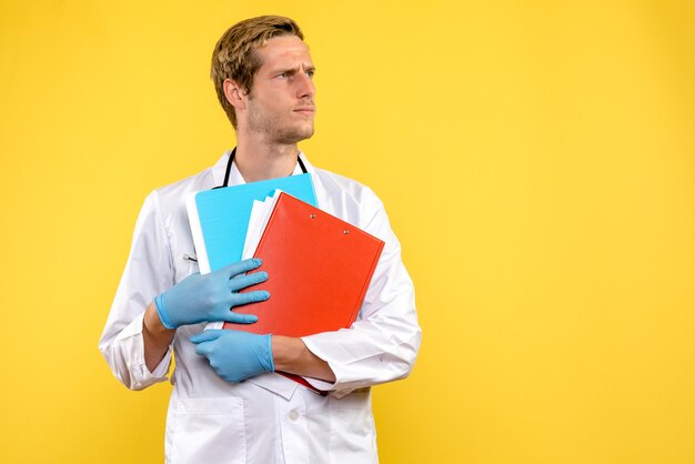 Front view male doctor holding analyzes on a yellow background health medic virus human