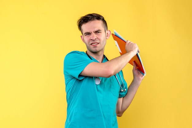 Вид спереди мужского врача, держащего анализы на желтой стене