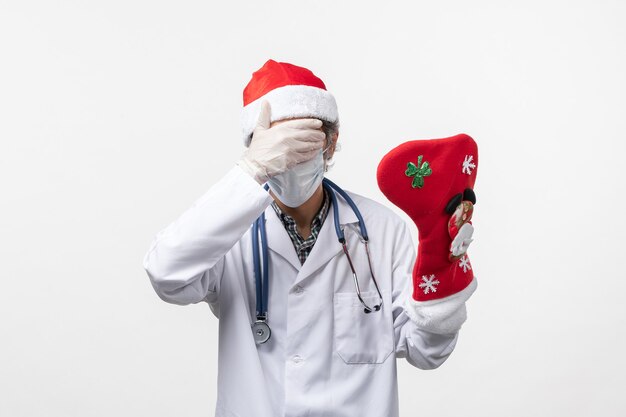 Front view male doctor holding big holiday sock on the white wall virus covid- holiday