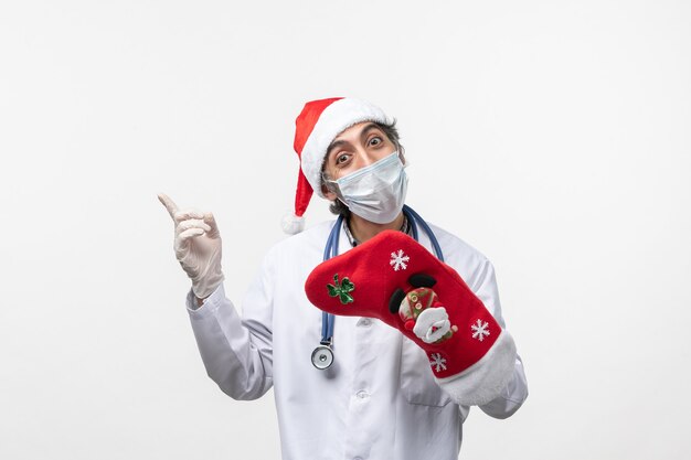 Front view male doctor holding big red sock on a white wall virus covid- holiday