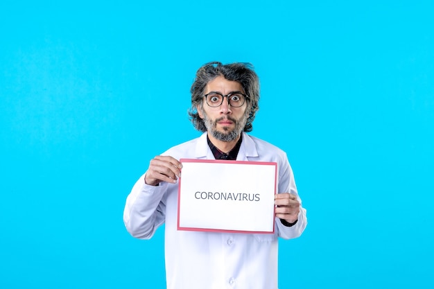 Front view male doctor holding coronavirus writing on blue