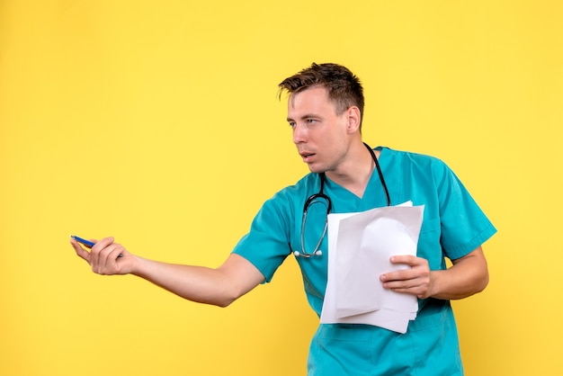 Free photo front view of male doctor holding documents on yellow wall