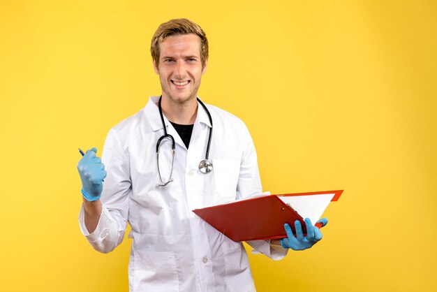 Front view male doctor holding file with notes on yellow desk health medic human virus