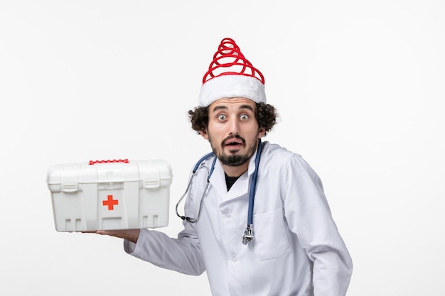 Вид спереди мужского врача, держащего аптечку на белой стене