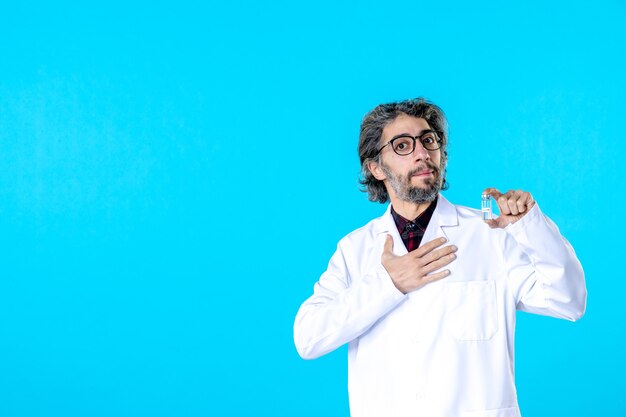 Front view male doctor holding little flask on blue