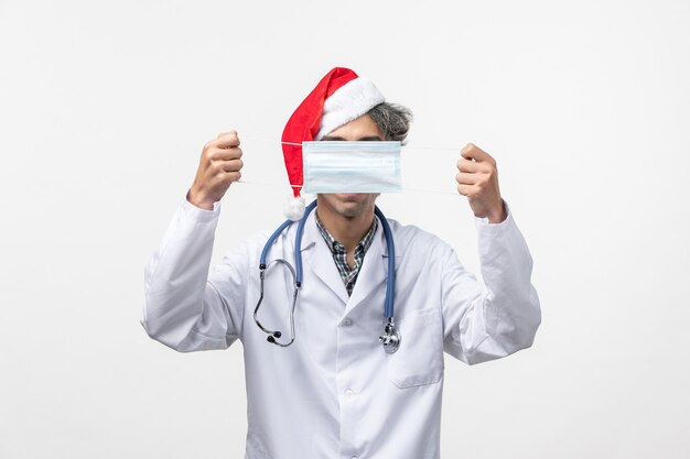 흰 벽 새해 휴일 바이러스 COVID에 마스크를 들고 전면보기 남성 의사