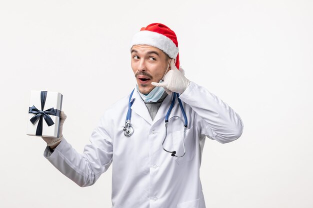 Front view of male doctor holding present on white wall