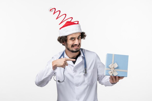Front view of male doctor holding present on white wall