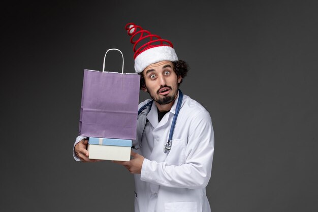 暗い壁にプレゼントを保持している男性医師の正面図