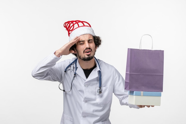 白い壁にプレゼントを保持している男性医師の正面図