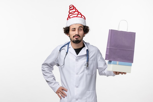 白い壁にプレゼントを保持している男性医師の正面図