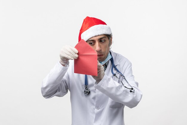 Front view male doctor holding red envelop on a white wall virus covid- health